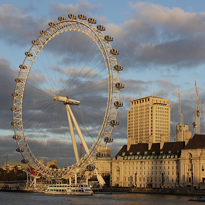 Photo of the London Eye on the South Bank at sunset, with city buildings and cranes in the background – a recognisable symbol of London.